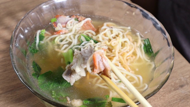 男子吃着鸡蛋面和红烧猪肉和虾馄饨视频素材