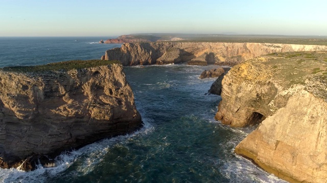 在葡萄牙圣文森特角(Cabo de Sao Vicente)，飞过波浪起伏的大西洋和覆盖着绿色苔藓的黄色岩石。这个地方是葡萄牙和欧洲大陆的最西南角。空中,UHD视频素材