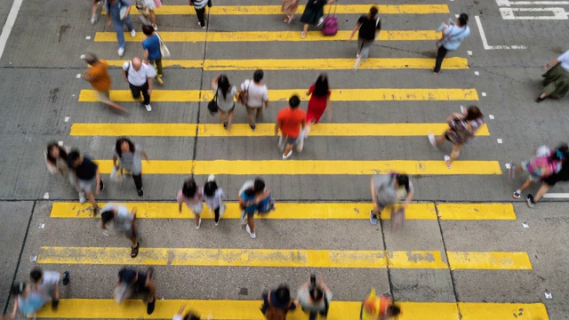 在香港孟角区，一群无法辨认的行人和汽车在黄色斑马线上行走视频素材