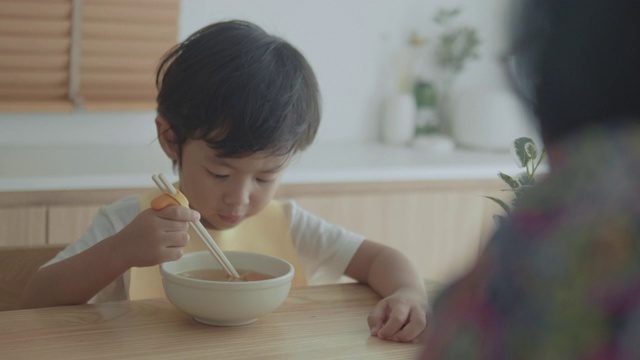 奶奶和孙女在餐桌上吃面条视频素材