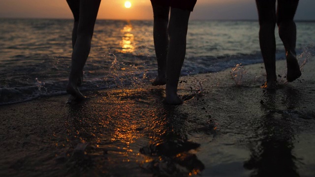 快乐的朋友们在希腊的夏日沙滩上跑步，在美丽的夕阳下游泳视频素材