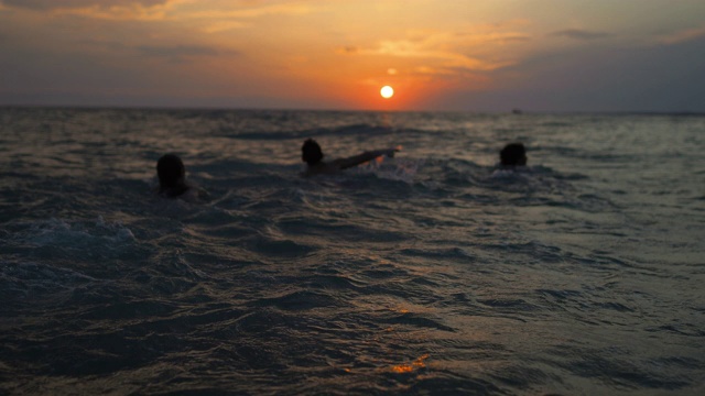 快乐的朋友们在希腊的夏日沙滩上跑步，在美丽的夕阳下游泳视频素材