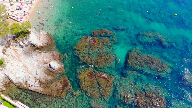 鸟瞰图的科斯塔布拉瓦天堂海滩在夏天和人们在清澈的水域游泳。视频素材