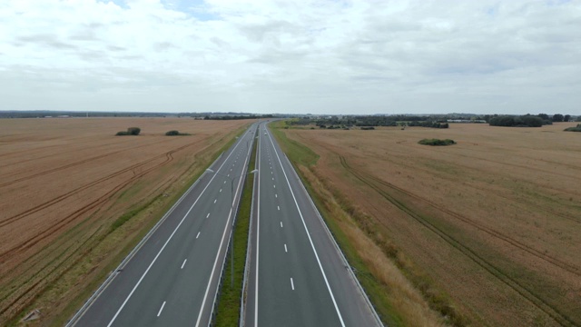 公路旅行在贫瘠的景观高速公路上飞过汽车。4 k。麦田之间的柏油路鸟瞰图。汽车在旱地上行驶的鸟瞰图。视频素材