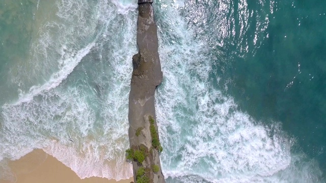 顶视图的海岸岩石和碰撞海洋颜色的波浪视频素材