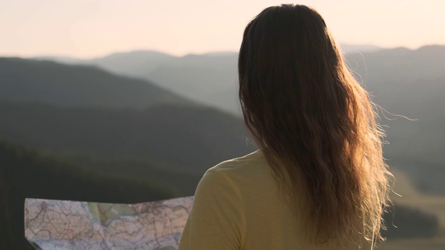 肖像。一位长发女游客手里拿着地图站在悬崖边，正在寻找旅游路线。视频素材