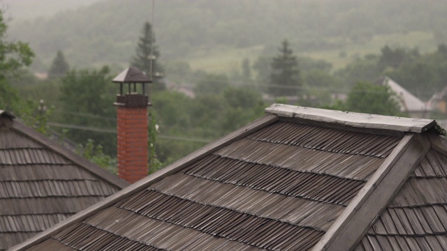 村子在阴雨阴沉的山区里。前景是一座传统的老房子的屋顶。乡村景观视频素材