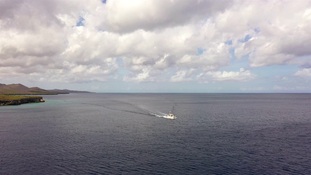 鸟瞰图的船在Curaçao海岸在加勒比海碧绿的水，悬崖，海滩和美丽的珊瑚礁周围Playa Forti视频素材