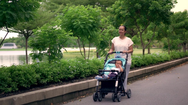 妈妈和她的女儿在公园里推着婴儿车视频素材