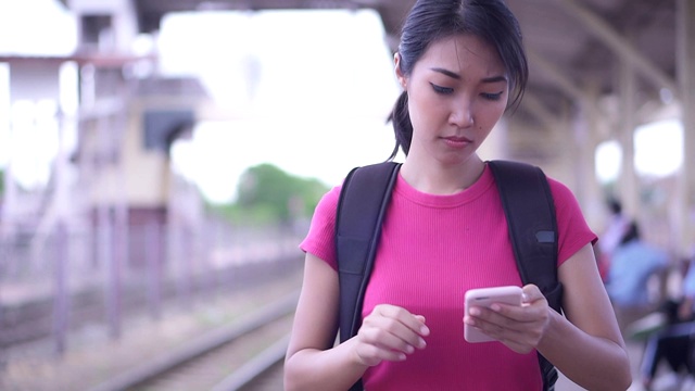 亚洲女性游客正在火车站用手机检查旅行。视频素材