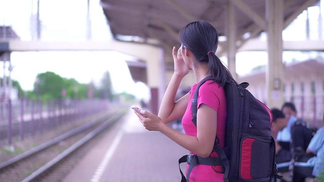 亚洲女性游客正在火车站用手机检查旅行。视频素材