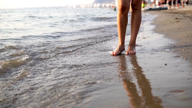 光着脚的女人走在夏天的海边特写，慢镜头视频素材