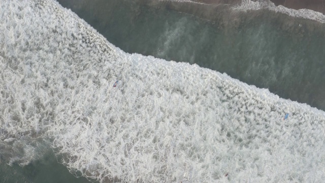 鸟瞰图的海滩与人们冲浪在印尼巴厘岛视频素材