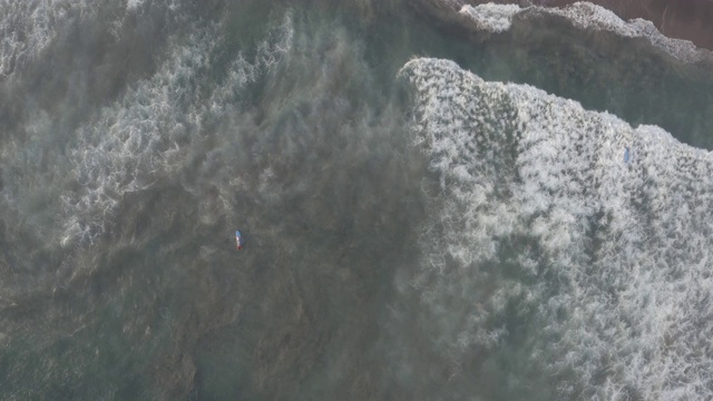 鸟瞰图的海滩与人们冲浪在印尼巴厘岛视频素材