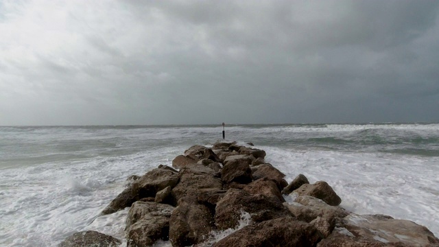 一段慢动作镜头:一场暴风雨在海滩上，巨浪冲击着岩石防波堤(防波堤)视频素材