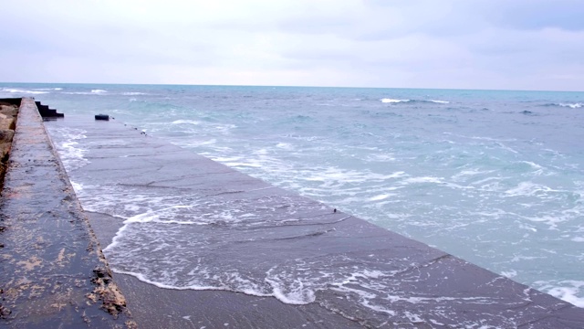 强烈的暴风雨海浪拍打着防波堤，水面飞溅。视频素材