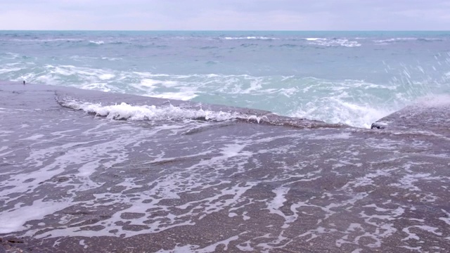 强烈的暴风雨海浪拍打着岸边的防波堤，美丽的水花飞溅。视频素材