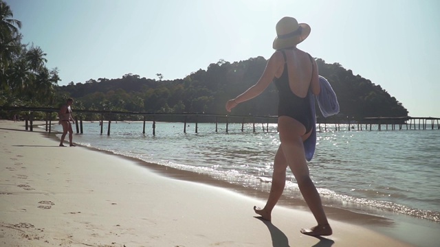 年轻女子沿着海边的沙滩散步视频下载