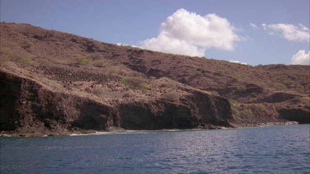 宽角度的海浪撞击岩石海岸与贫瘠的山或悬崖在bg。海洋。沿着海岸行驶的汽车。视频素材