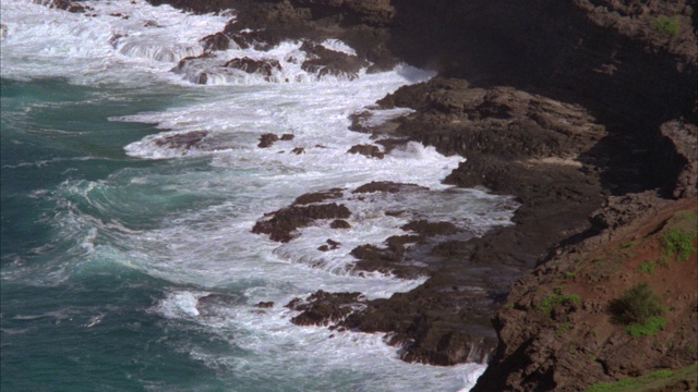 海浪拍打着悬崖，岩石嶙峋的海岸线，海湾。海洋。可能是在热带地区。视频素材