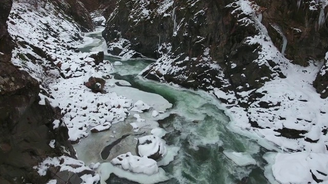 峡谷底部冰冷的河流岩石上有冰柱视频素材