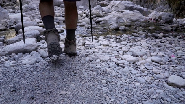 一个旅游者拿着登山杖沿着峡谷行走。慢动作视频素材