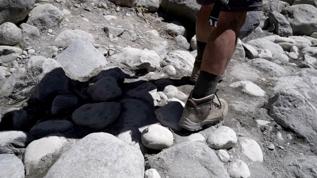 一个旅游者拿着登山杖沿着峡谷行走。慢动作视频素材