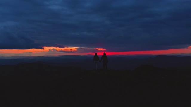 男人和女人站在山顶上，在夕阳的背景下视频素材