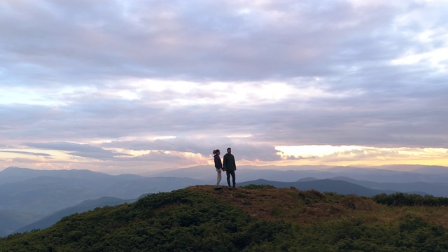 这对夫妇站在山顶上，以日出为背景视频素材