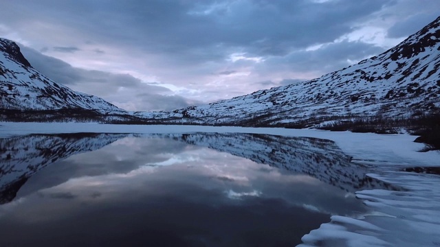 白雪覆盖的山脉倒映在湖面上。视频素材