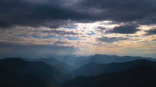 在阳光明媚的背景上，云在群山之上流动。时间流逝视频素材