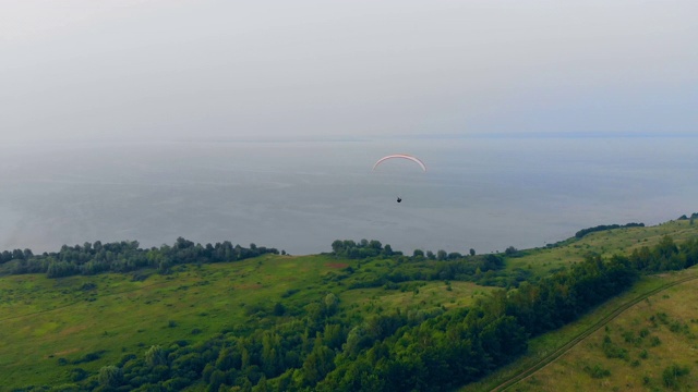 一架滑翔机正在田野上空向水面飞行。降落伞跳伞手法。视频素材