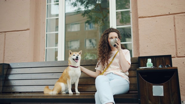 快乐的年轻女人在咖啡馆喝茶和抚摸可爱的柴犬狗视频素材