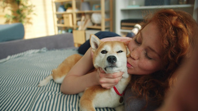 快乐的女孩亲吻柴犬，并拿着相机自拍视频素材