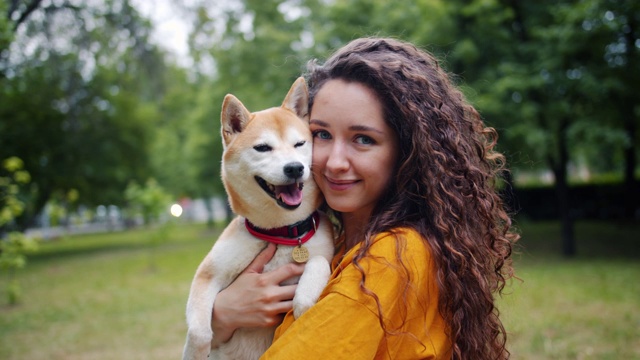 可爱的女孩爱狗主人站在公园和她美丽的宠物微笑的肖像视频素材