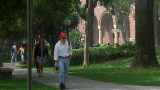 广角的学生，人们走在人行道上的学院，大学或常青藤联盟校园。草地、树木和多层砖房。南加州大学校园。视频素材