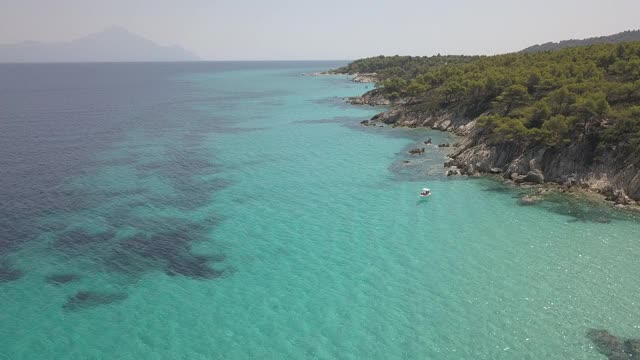 鸟瞰图的小海滩与绿松石水旁边的岩石和树木在Agia Paraskevi Halkidiki地区，希腊。从无人机视频素材