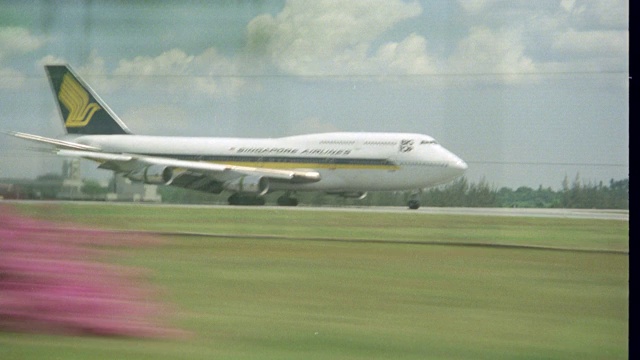 新航747“大顶”飞机在乡村机场降落时，从汽车保险杠后向左的广角移动pov /4。fg的树木和灌木丛。飞机。商业客机。客机。视频素材