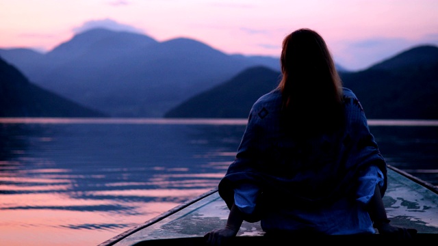 夕阳中坐在船头的女人视频素材