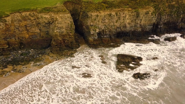 无人机在岩石嶙峋的海岸线上空飞行。视频素材