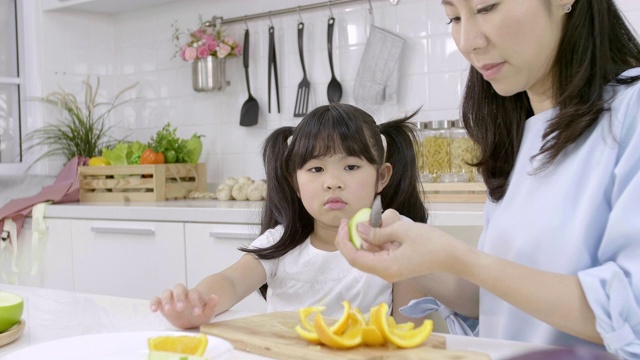 快乐的亚洲家庭小女孩享受和妈妈在厨房准备蔬菜和水果在家里。健康食品的概念视频素材