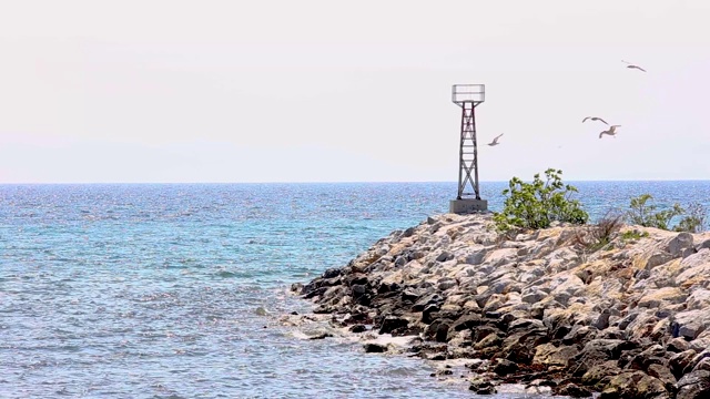 石头防波堤和建筑蓝色海洋航行，海鸥飞行，希腊哈尔基迪基视频素材