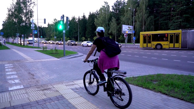 骑自行车的女人，在街上骑自行车的女人，急匆匆地穿过十字路口，但遇到红灯，停下来等待绿灯信号视频素材