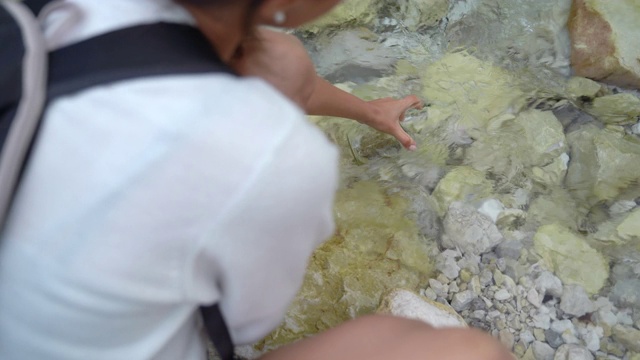 年轻女子用新鲜的河水装满水瓶并喝了一些视频素材