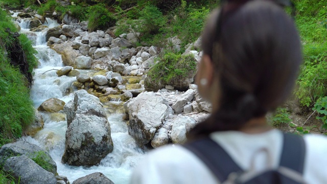 年轻女子在徒步旅行中看着流水视频素材