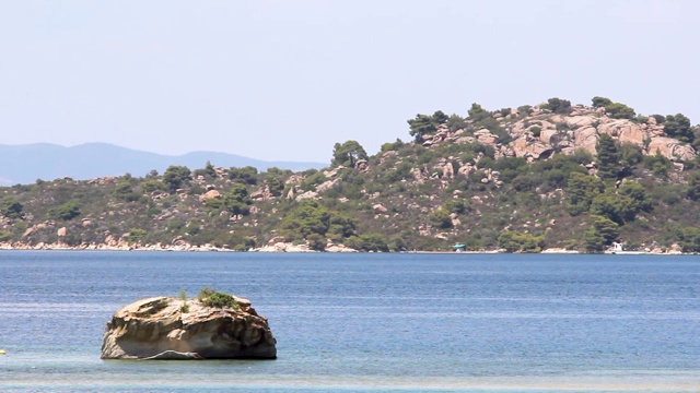 希腊Halkidiki，田园诗般的海岸，海边有树木的岩石，中间有一块孤零零的岩石视频素材