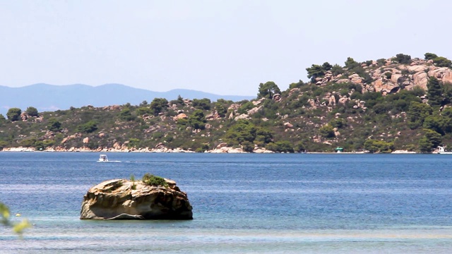 希腊Halkidiki，田园诗般的海岸，海边有树木的岩石，中间有一块孤零零的岩石视频素材