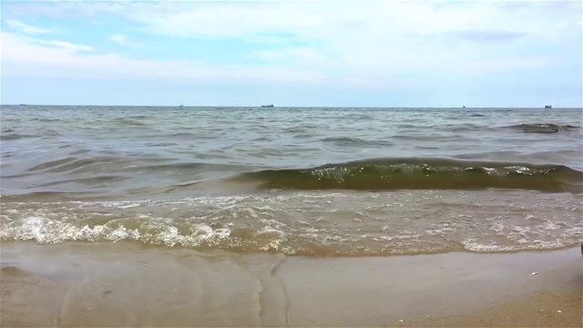 一个女人走在海边，海浪抚摸着她的脚。视频素材