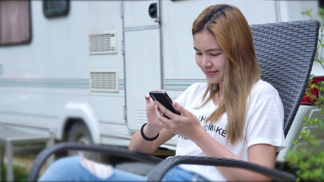 亚洲女人在露营车前玩手机视频素材