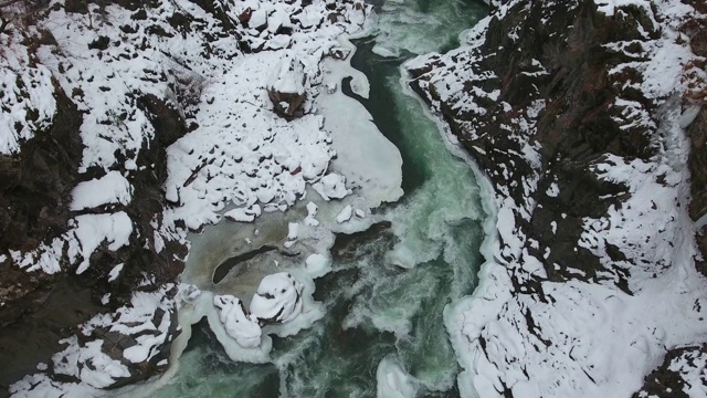 在白雪覆盖的峡谷底部，碧绿的水流湍急视频素材